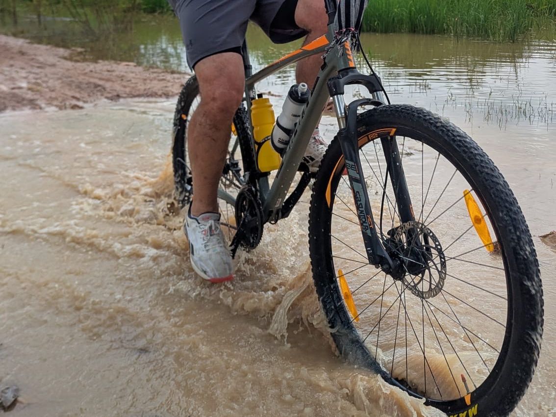 One of our standard mountain bikes being ridden through a flooded dirt road