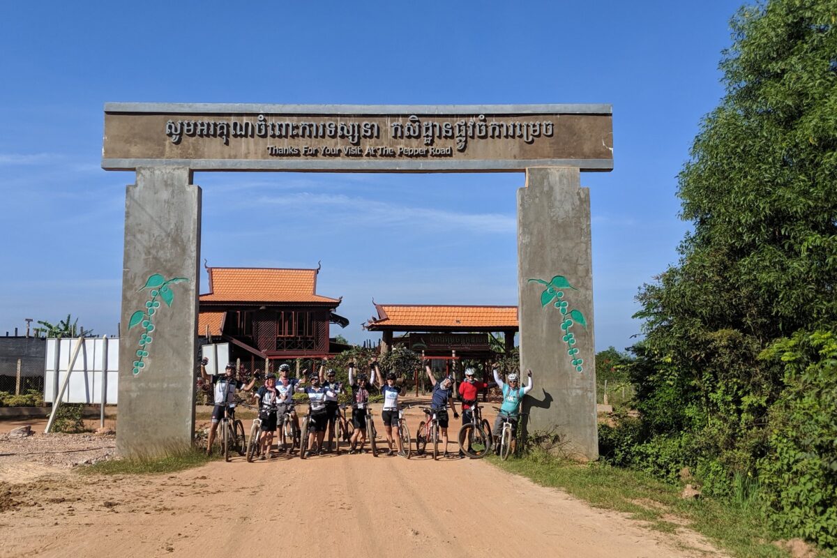 The group raising their arms under the Pepper Road farm gate, bikes in hand