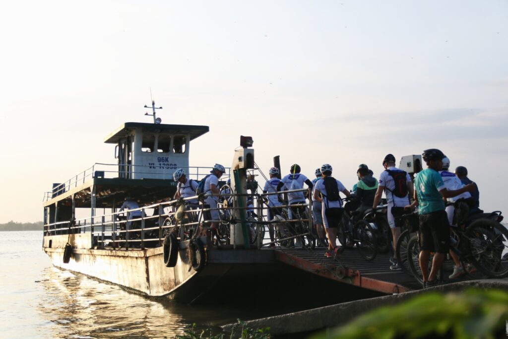 Riders and bikes boarding a river ferry in the Mekong Delta