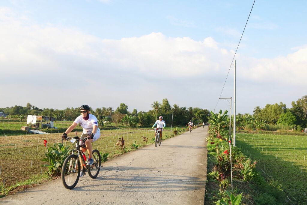 Riders on a concrete path between fields in the Mekong Delta