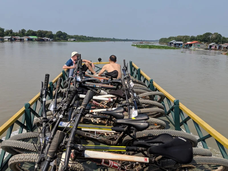 Bikes stacked along the bow on the river from Siem Reap, floating houses on both banks