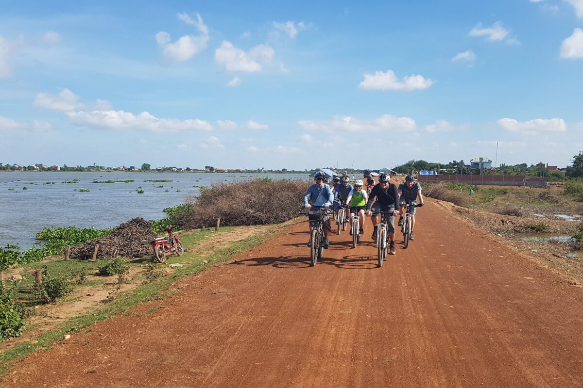 The group rides a red dyke road along the river