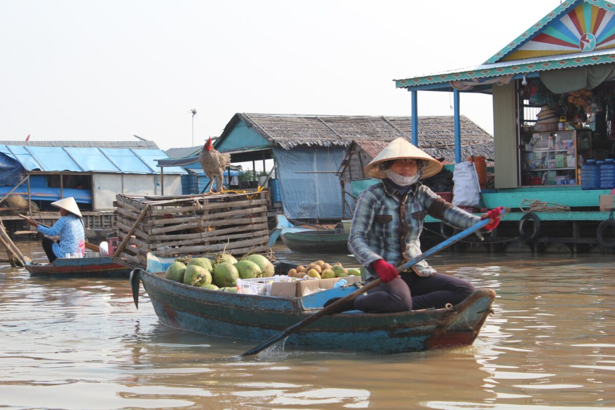 A woman paddles her fruit boat through a floating village