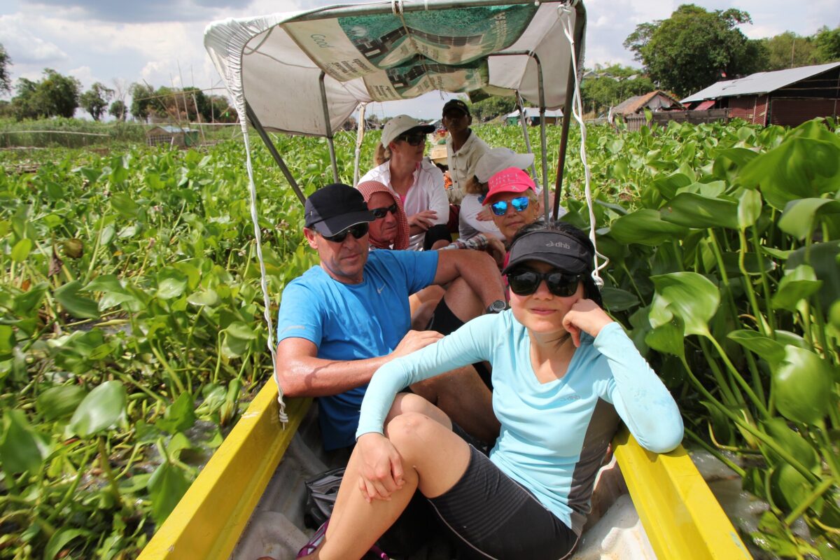 Riders squeeze into a small boat through the water hyacinth