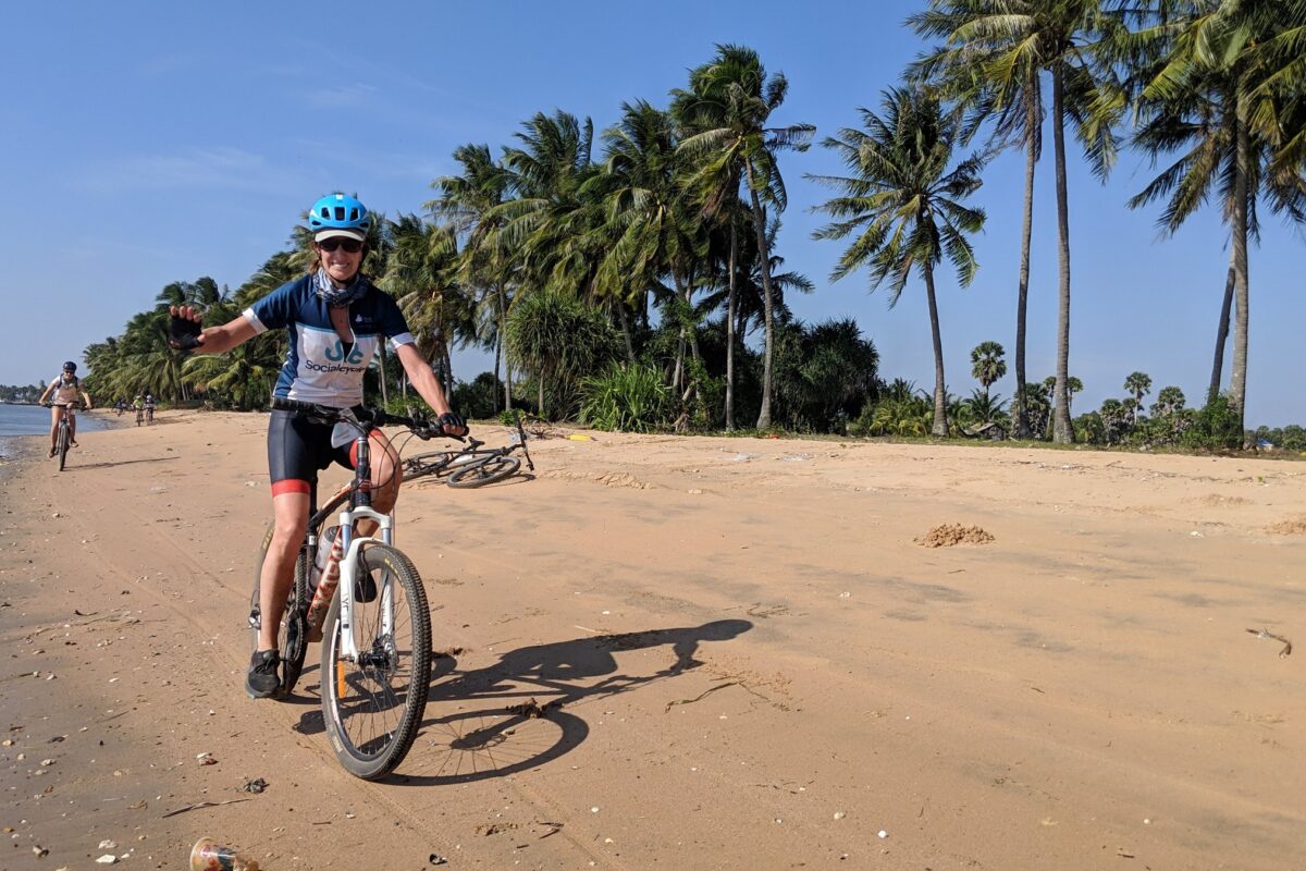 A rider waves from a palm-fringed beach near Kep, the group along the water