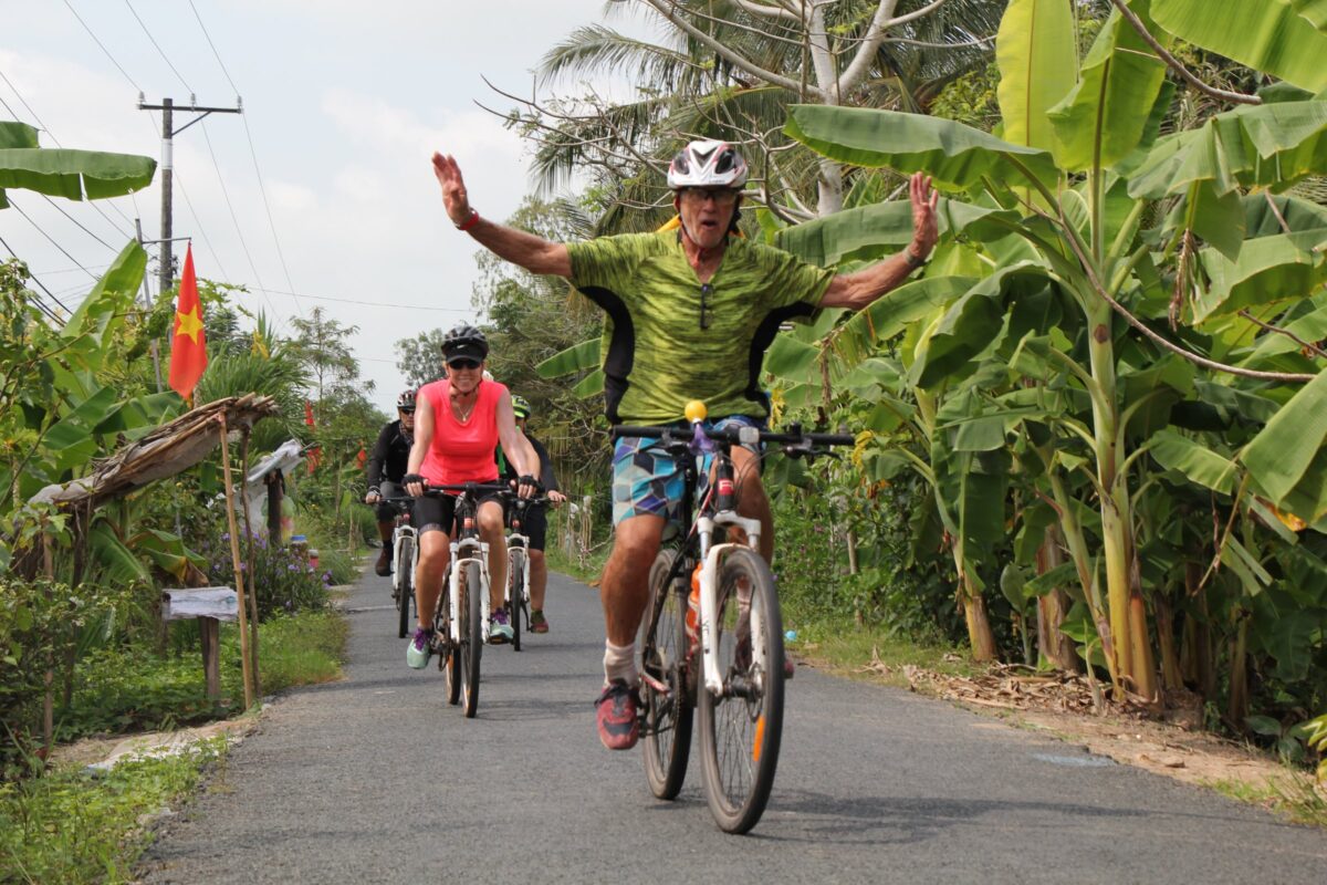 A grinning rider throws his arms wide on a banana-lined lane