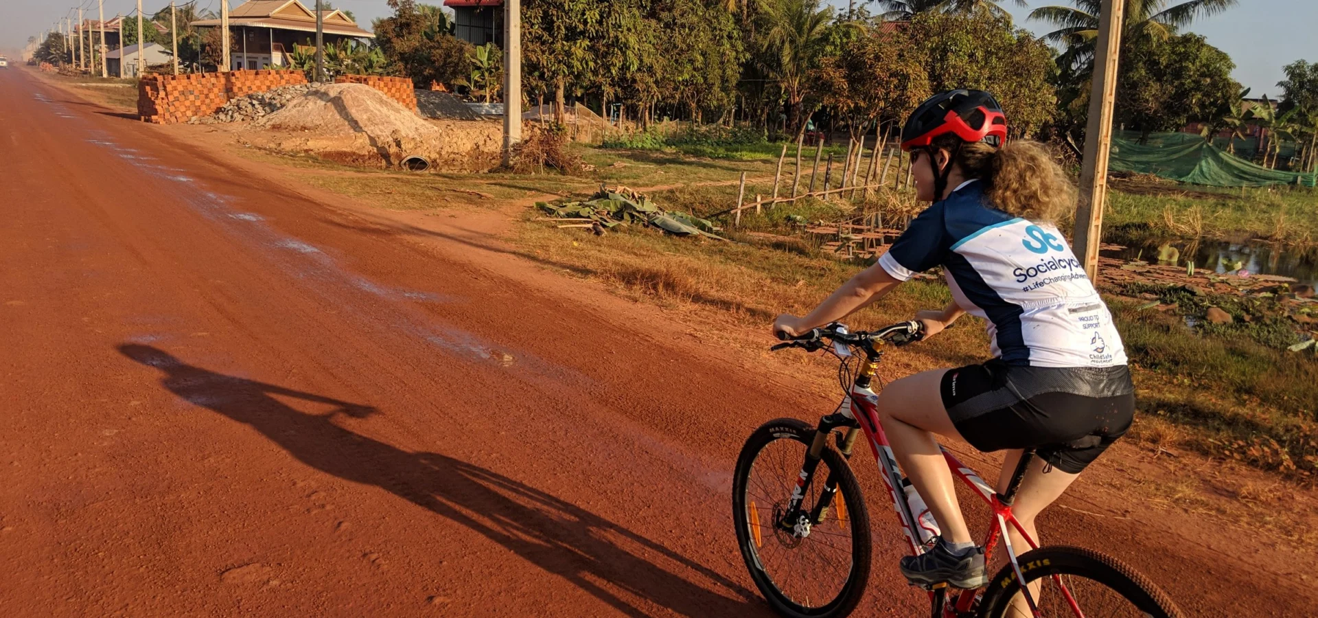 A rider on a red dirt road near Siem Reap, Cambodia, in early morning light