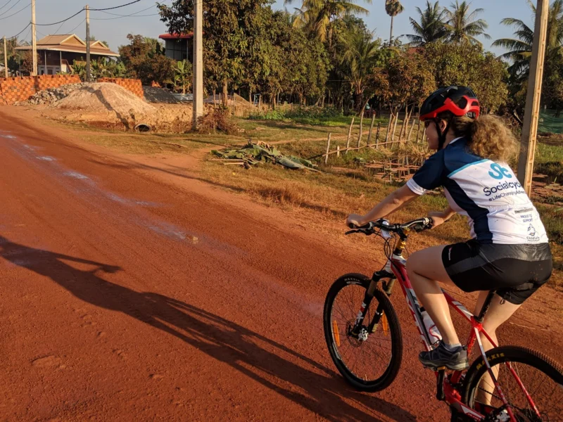 A rider on a red dirt road near Siem Reap, Cambodia, in early morning light