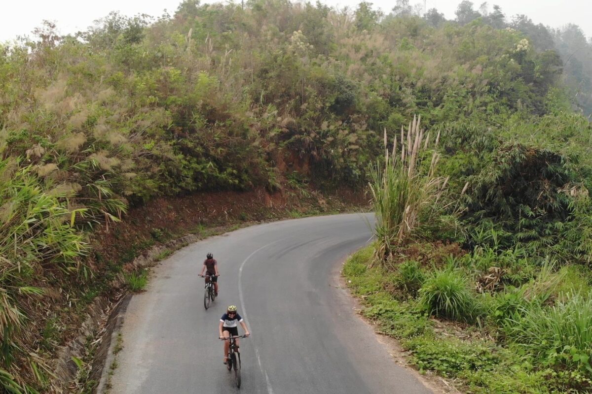 From the air: two riders round a curving hillside road