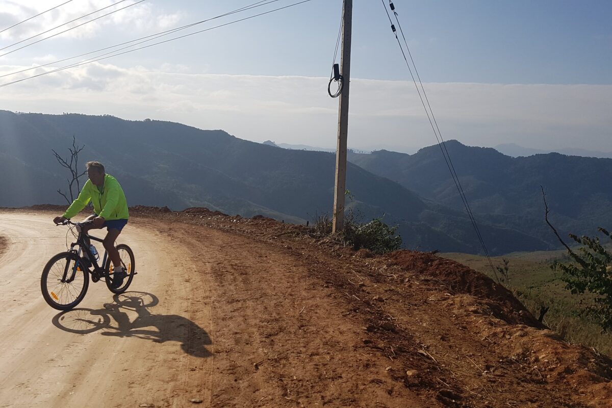 A rider on a red-dirt mountain bend, sun rays over the ridges