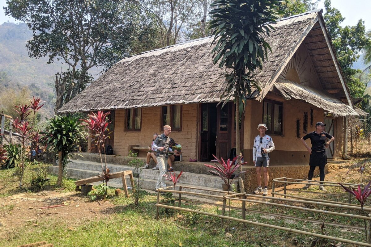 Riders rest outside an earth-walled cottage in a northern Laos village